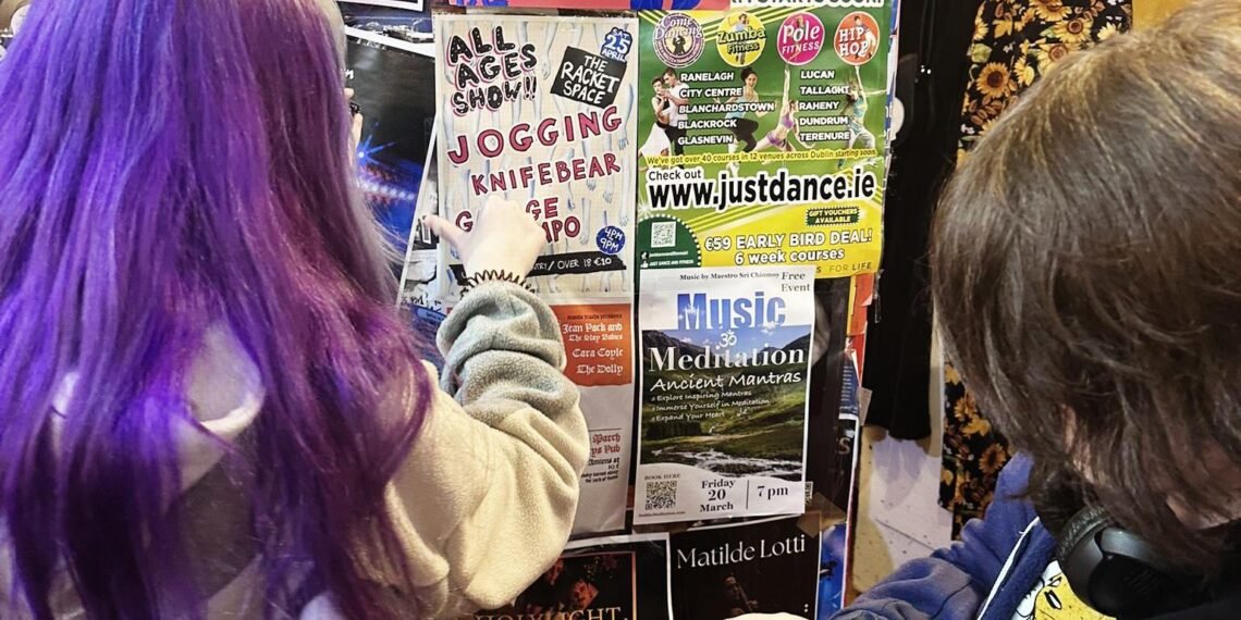 Due bambini indicano il volantino del concerto “Dublino, la musica senza gerarchie: al Racket Space il rito collettivo della scena DIY”, in programma il 25 aprile a Dublino