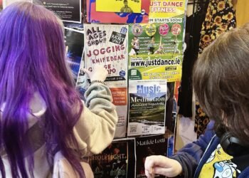 Due bambini indicano il volantino del concerto “Dublino, la musica senza gerarchie: al Racket Space il rito collettivo della scena DIY”, in programma il 25 aprile a Dublino