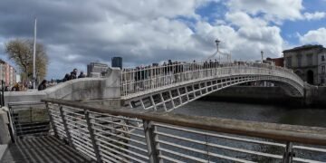 Ha'penny Bridge, Dublino. Il celebre Ha'penny Bridge attraversa il fiume Liffey in una rara giornata di sole nel cuore di Dublino. Simbolo storico della capitale irlandese, il ponte rappresenta ancora oggi uno dei luoghi più iconici della città, meta quotidiana di residenti, lavoratori e turisti.