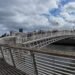Ha'penny Bridge, Dublino. Il celebre Ha'penny Bridge attraversa il fiume Liffey in una rara giornata di sole nel cuore di Dublino. Simbolo storico della capitale irlandese, il ponte rappresenta ancora oggi uno dei luoghi più iconici della città, meta quotidiana di residenti, lavoratori e turisti.