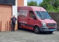 Francesco Morelli accanto al suo inconfondibile Mercedes Sprinter rosso, personalizzato con immagini panoramiche di Casalattico e Cashel, simbolo del lungo viaggio che collega l'Italia all'Irlanda.