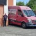 Francesco Morelli accanto al suo inconfondibile Mercedes Sprinter rosso, personalizzato con immagini panoramiche di Casalattico e Cashel, simbolo del lungo viaggio che collega l'Italia all'Irlanda.