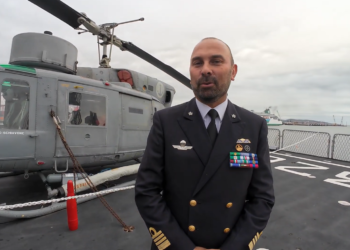 Alessandro De Lucia, comandante di Nave Etna, sul ponte di volo dell’unità della Marina Militare Italiana, con alle spalle l’elicottero di bordo.