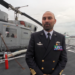 Alessandro De Lucia, comandante di Nave Etna, sul ponte di volo dell’unità della Marina Militare Italiana, con alle spalle l’elicottero di bordo.